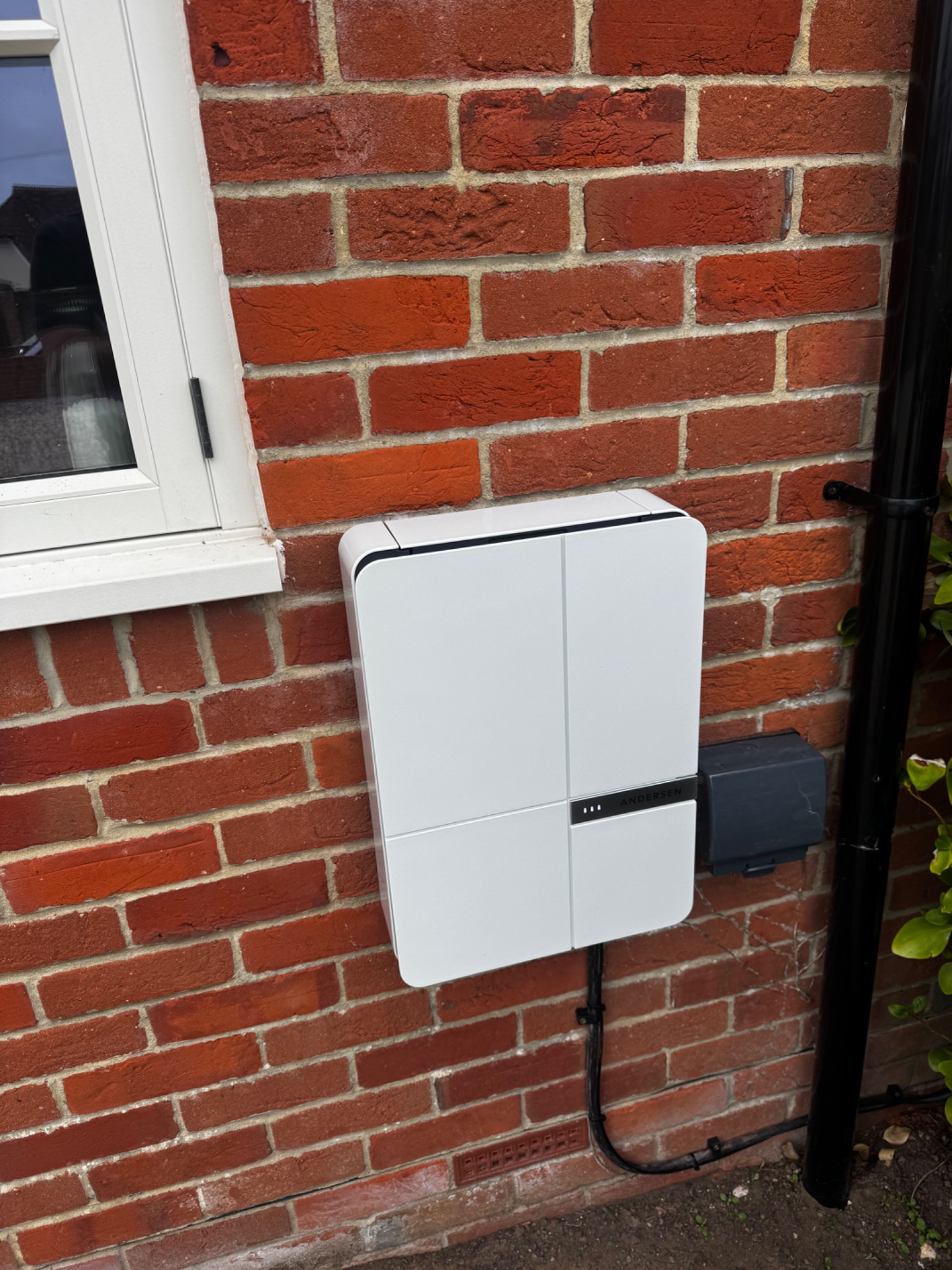 Andersen EV charger installed on the outside brick wall of a home